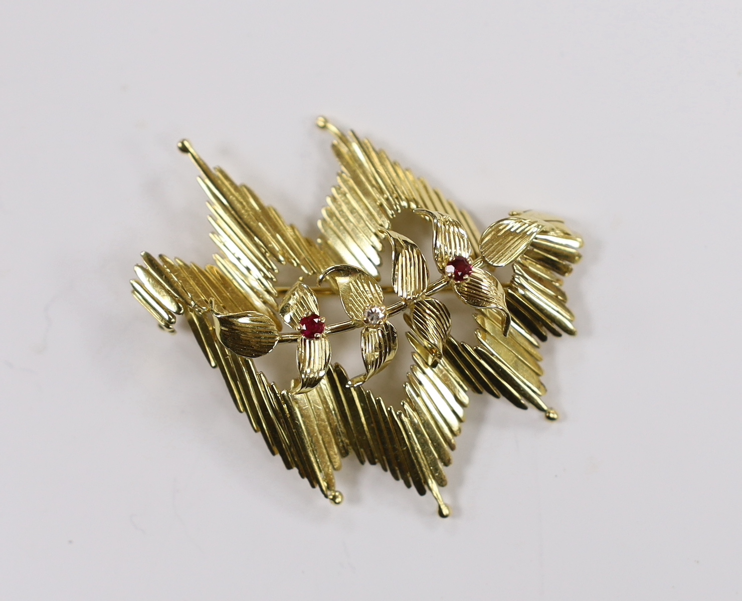 A 1960's 18ct gold, ruby and diamond set stylised foliate brooch, 45mm, gross weight 12.3 grams.